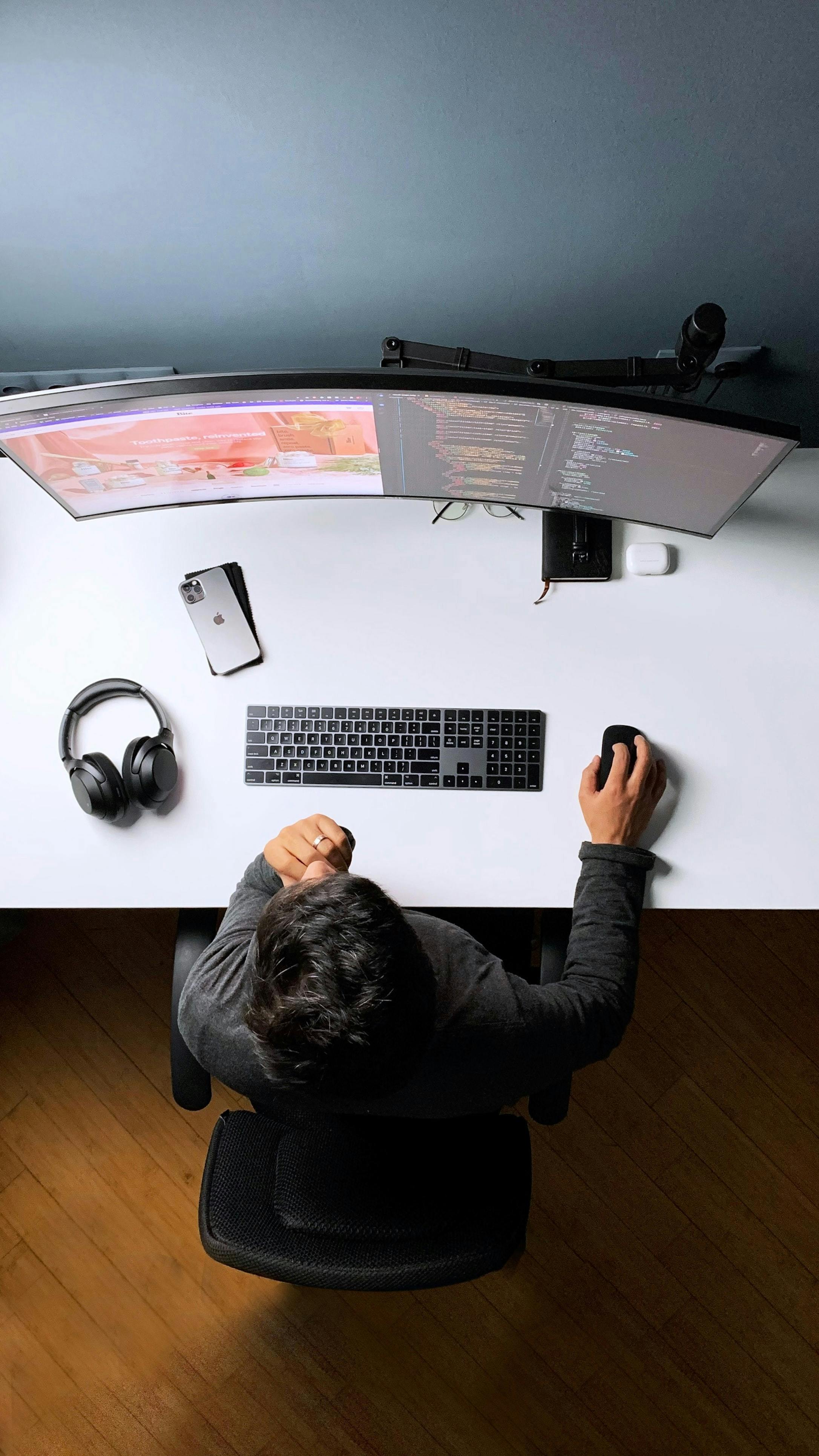 Woman near computer looking at her watch.
